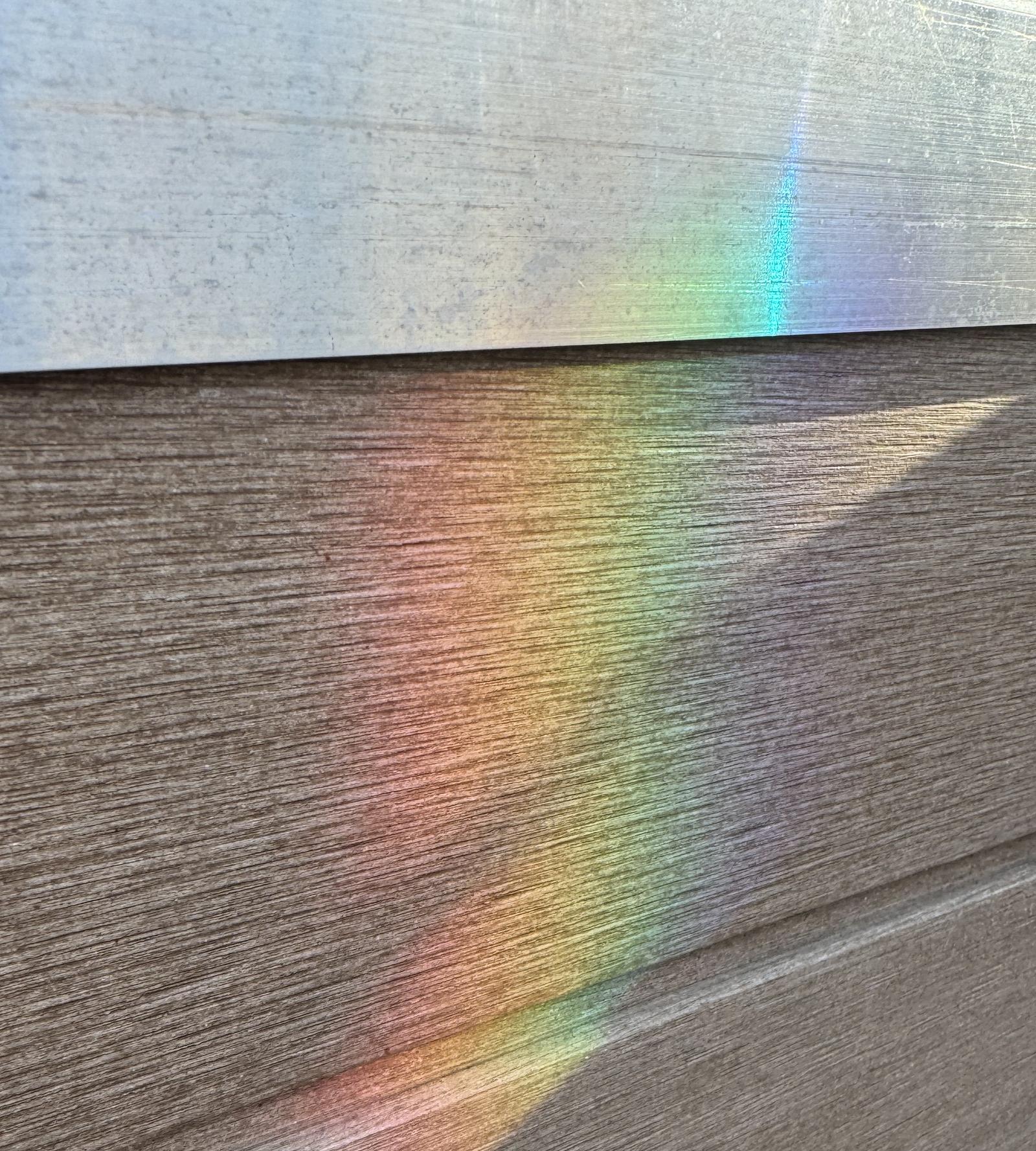 A rainbow of light cast across wood siding